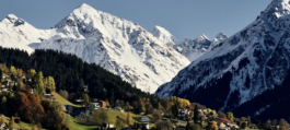 Snow capped mountains above a Alpine town with trees Woodhall Ventures -